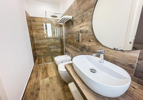 a bathroom with a sink and a mirror and a toilet at Piccolo Torino Rooms in Canicattì