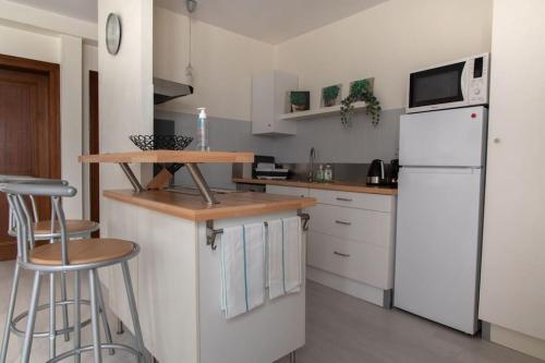 Il comprend une cuisine équipée d'appareils électroménagers blancs et d'un réfrigérateur blanc. dans l'établissement Le Sebastopol - Appt moderne de 65m2, à Strasbourg