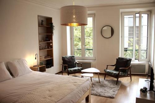 - une chambre avec un lit, deux chaises et un lustre dans l'établissement Le Sebastopol - Appt moderne de 65m2, à Strasbourg