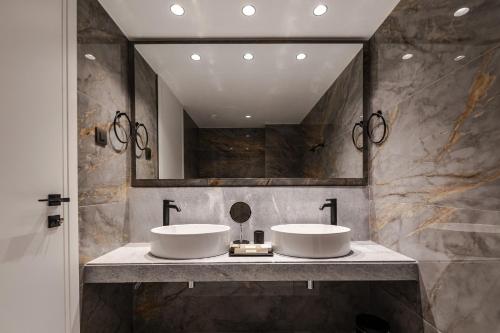 a bathroom with two sinks and a large mirror at Magnes Hotel in Volos