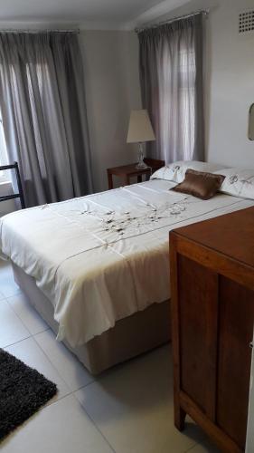 a bedroom with a large white bed with a table at Alcamal in Cape Town