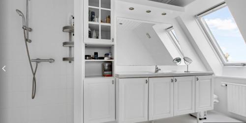 Baño blanco con lavabo y espejo en 4 bedroom 200m2 luxury house with garden in Horsens, en Horsens