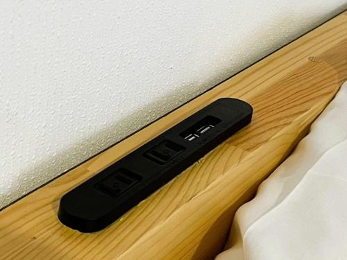 a black remote control sitting on the side of a bed at IshiuchiBASE in Minami Uonuma