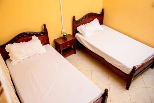 two twin beds in a room with a table at Exotic Inn and Apartments in Kampala