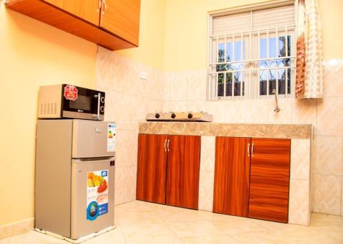 a kitchen with a refrigerator and a microwave at Exotic Inn and Apartments in Kampala