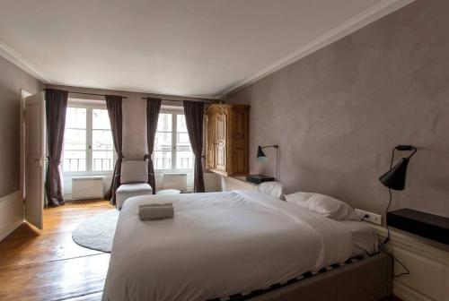 une chambre avec un grand lit blanc et deux fenêtres dans l'établissement Tonneliers, à Strasbourg