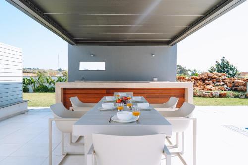 a dining room with a table and white chairs at Vivo Mare Beachfornt Villas - Azure in Ayia Napa