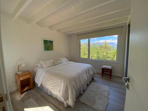 Un dormitorio con una cama y una ventana grande. en Moderna casa en el bosque, en San Martín de los Andes