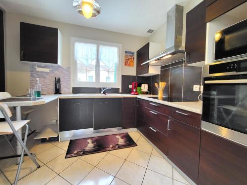 une cuisine avec des placards bruns et une table. dans l'établissement La Campagnarde : Havre de paix nature proche Paris, à Champlan