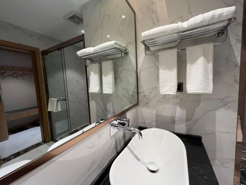 Baño blanco con lavabo y espejo en Zhangjiajie lollipop Hotel, en Zhangjiajie