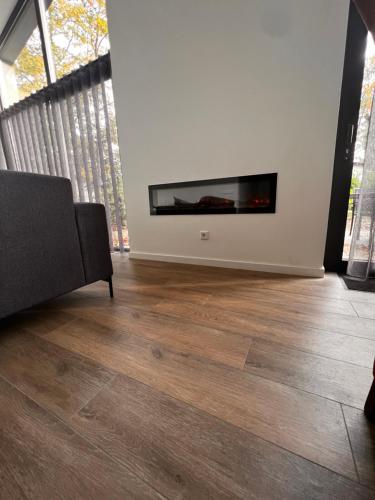 a living room with a fireplace and wooden floors at Luxe recreatiewoning midden in bosrijke omgeving in Waalre