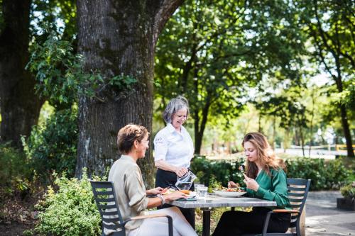 three women sitting at a table in a park at 50|50 Hotel Belmont in Ede