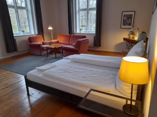 a bedroom with a bed and chairs and a lamp at Hotel Pelli Hof Rendsburg by Tulip Inn in Rendsburg