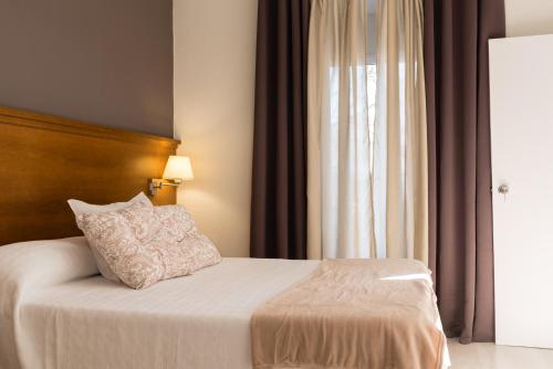 Schlafzimmer mit einem Bett mit einem Kissen und einem Fenster in der Unterkunft Hostal Imperial in Merida