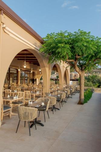 an outdoor patio with tables and chairs and trees at Blue Sea Beach Affiliated By Melia in Stalida