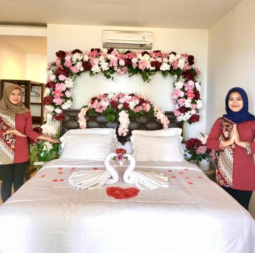 two women standing next to a large bed with flowers at Keraton Krakatoa in Banten