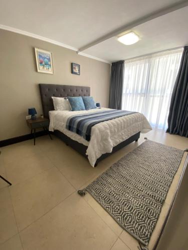 1 dormitorio con 1 cama grande y 1 alfombra en Marina Bay Apartment, en Durban