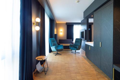 a room with blue chairs and a table and a kitchen at Artis Loft Hotel in Radziejowice