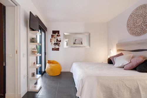 a white bedroom with a bed and a yellow vase at The Garden Secret in Villaverde