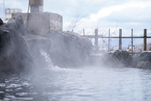 a body of water with rocks in the water at IshiuchiBASE in Minami Uonuma