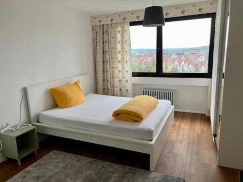 uma cama branca com almofadas amarelas num quarto com uma janela em Wohnung DC 12A em Neu-Ulm