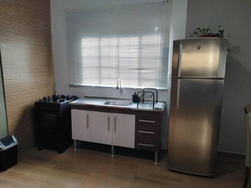 a kitchen with a stainless steel refrigerator and a sink at Casa aconchegante in Sao Jose do Rio Preto