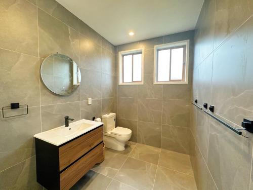 a bathroom with a sink and a toilet and a mirror at 4 Bedrooms Escape, close to CBD in Rotorua