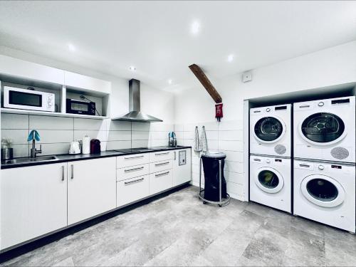 a white kitchen with two washer and dryer machines at Monteurzimmer - Worker's accommodation - ZIMMERzuVERMIETEN Oensingen in Oensingen
