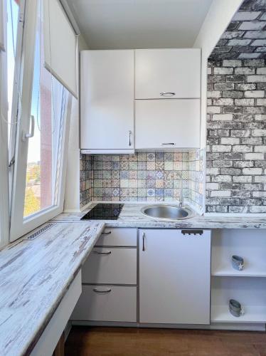 a kitchen with white cabinets and a brick wall at Радужная студия Вокзал Харьков-Пассажирский in Kharkiv