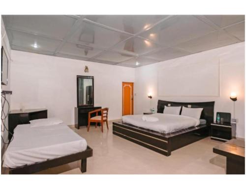 a bedroom with two beds and a table and a chair at Shiv Sutra Resorts, Mussoorie in Mussoorie
