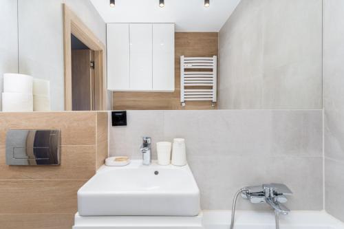 La salle de bains est pourvue d'un lavabo blanc et d'un miroir. dans l'établissement Bronowice Cosy Apartment, à Cracovie