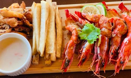 a plate of food with shrimp and bread and a sandwich at Bojo Beach Resort in Bortianor