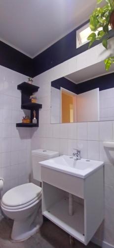 a white bathroom with a toilet and a sink at Esencia Cabaña in Potrerillos