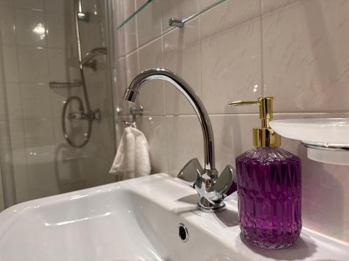 a purple vase sitting on a sink in a bathroom at Willa pod Bukami in Polanica-Zdrój
