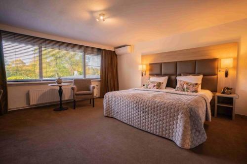 a hotel room with a large bed and a chair at Hotel Laurabos in Weert