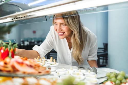 a woman standing behind a counter with food on a table at Hotel Villa del Mar in Benidorm