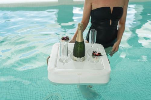 a woman in a pool with a tray with a bottle of champagne at Hotel Villa del Mar in Benidorm