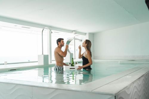 a man and a woman sitting in a swimming pool at Hotel Villa del Mar in Benidorm
