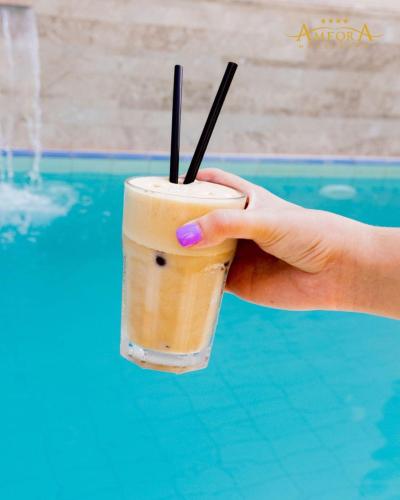 a hand holding a drink with two straws at Amfora Hotel & Spa in Durrës