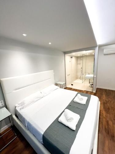 a bedroom with a large white bed and a bathroom at Botafoch Luxury Room in Ibiza Town
