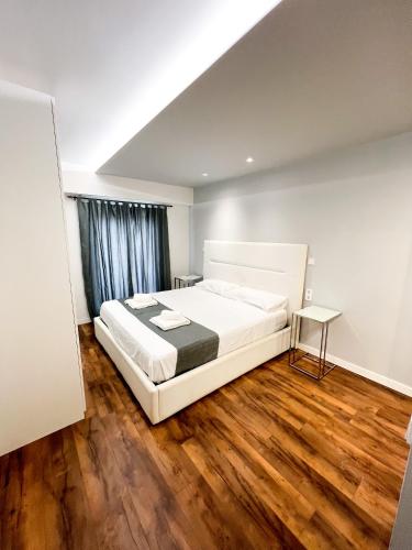 a bedroom with a white bed and a wooden floor at Botafoch Luxury Room in Ibiza Town