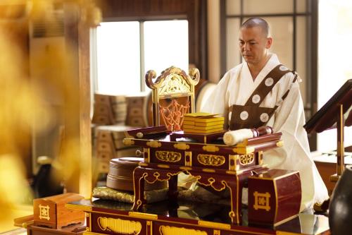 mężczyzna stojący przed stołem z aorah w obiekcie Temple Hotel 南アルプス法源寺 w mieście Minami Alps