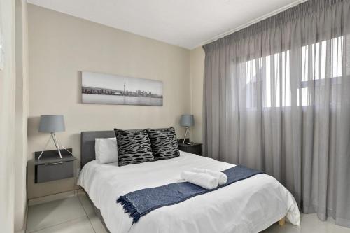 a bedroom with a bed and a large window at Marley on Katherine Apartments in Johannesburg