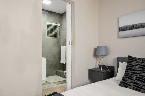 a bedroom with a bed and a bathroom with a shower at Marley on Katherine Apartments in Johannesburg