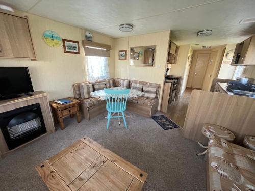 a living room with a couch and a table and a television at E4A, Three bedroom caravan - California Cliffs, Parkdean Resort, Scratby - Sleeps 8, bed linen and towels included - Pet Friendly - only 300m from the beach! in Great Yarmouth