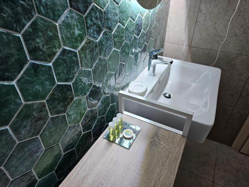 a bathroom with a white sink and green tiled walls at Plaza Residence in Braşov