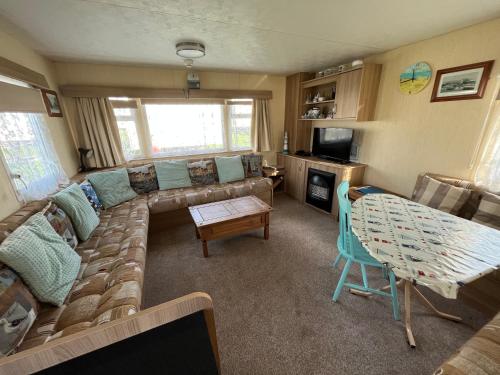 a living room with a couch and a table at E4A, Three bedroom caravan - California Cliffs, Parkdean Resort, Scratby - Sleeps 8, bed linen and towels included - Pet Friendly - only 300m from the beach! in Great Yarmouth