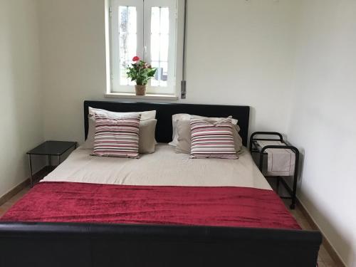 a bed with a red blanket and pillows on it at The Garden Room in Bombarral
