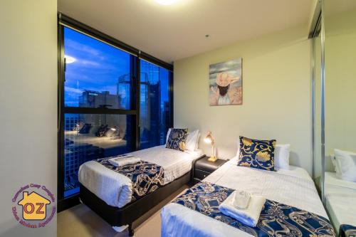 メルボルンにあるAussie Escape Apartmentsのベッドルーム1室(ベッド2台、大きな窓付)