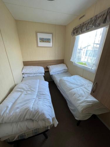 two beds in a small room with a window at Eagle 4a, Scratby - California Cliffs, Parkdean, sleeps 8, bed linen and towels included, pet friendly and close to the beach in Great Yarmouth
